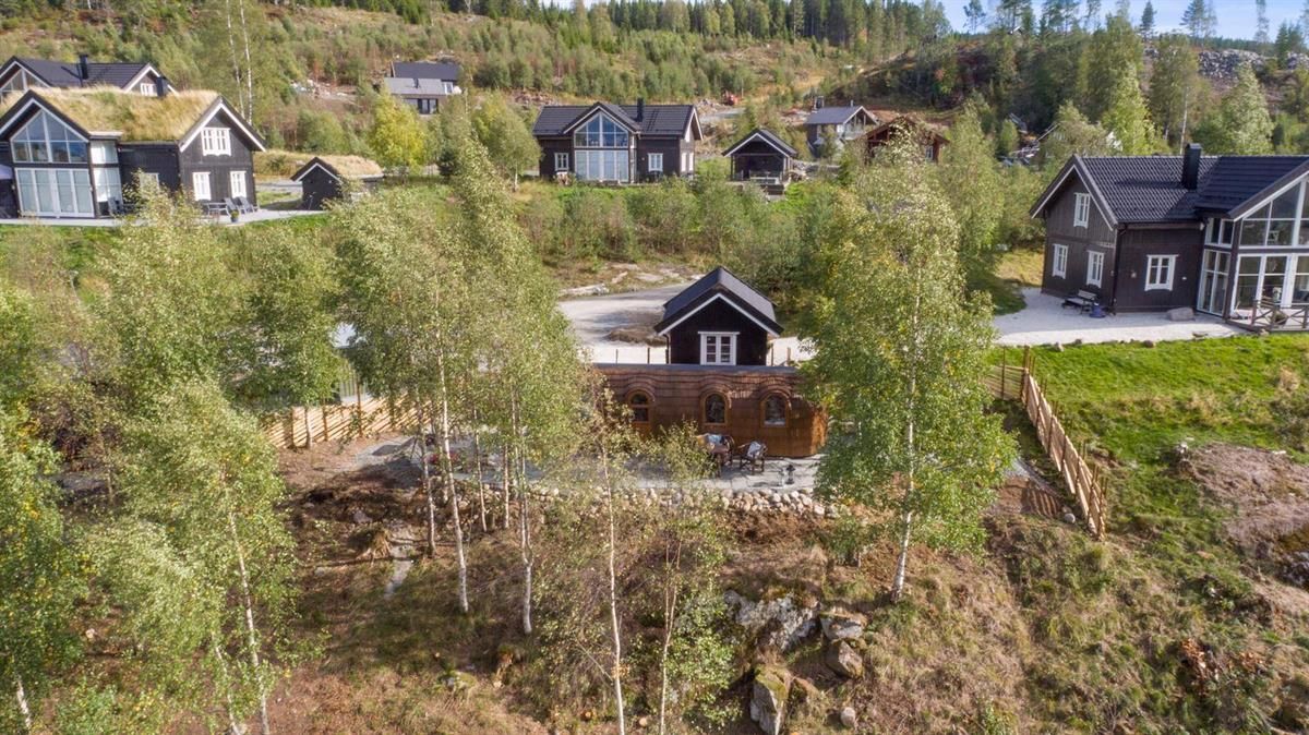Cabin area surrounded by trees and nature with several buildings in the background.