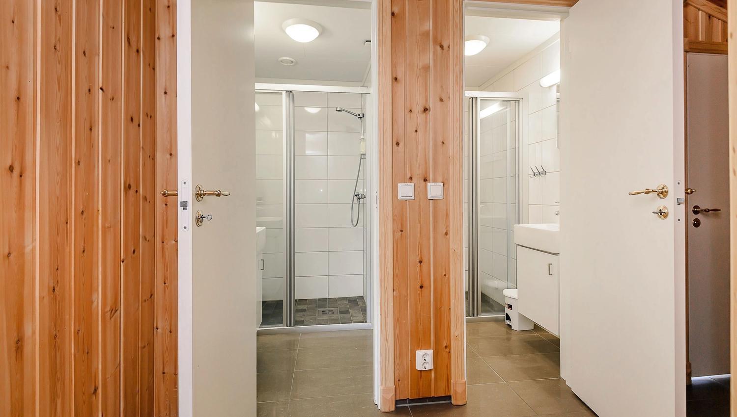 A bathroom with wood paneled wall and shower.