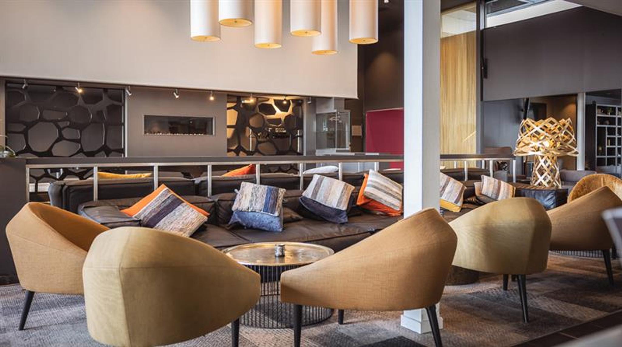 Hotel entrance with modern architecture, parking area, and clear signage.