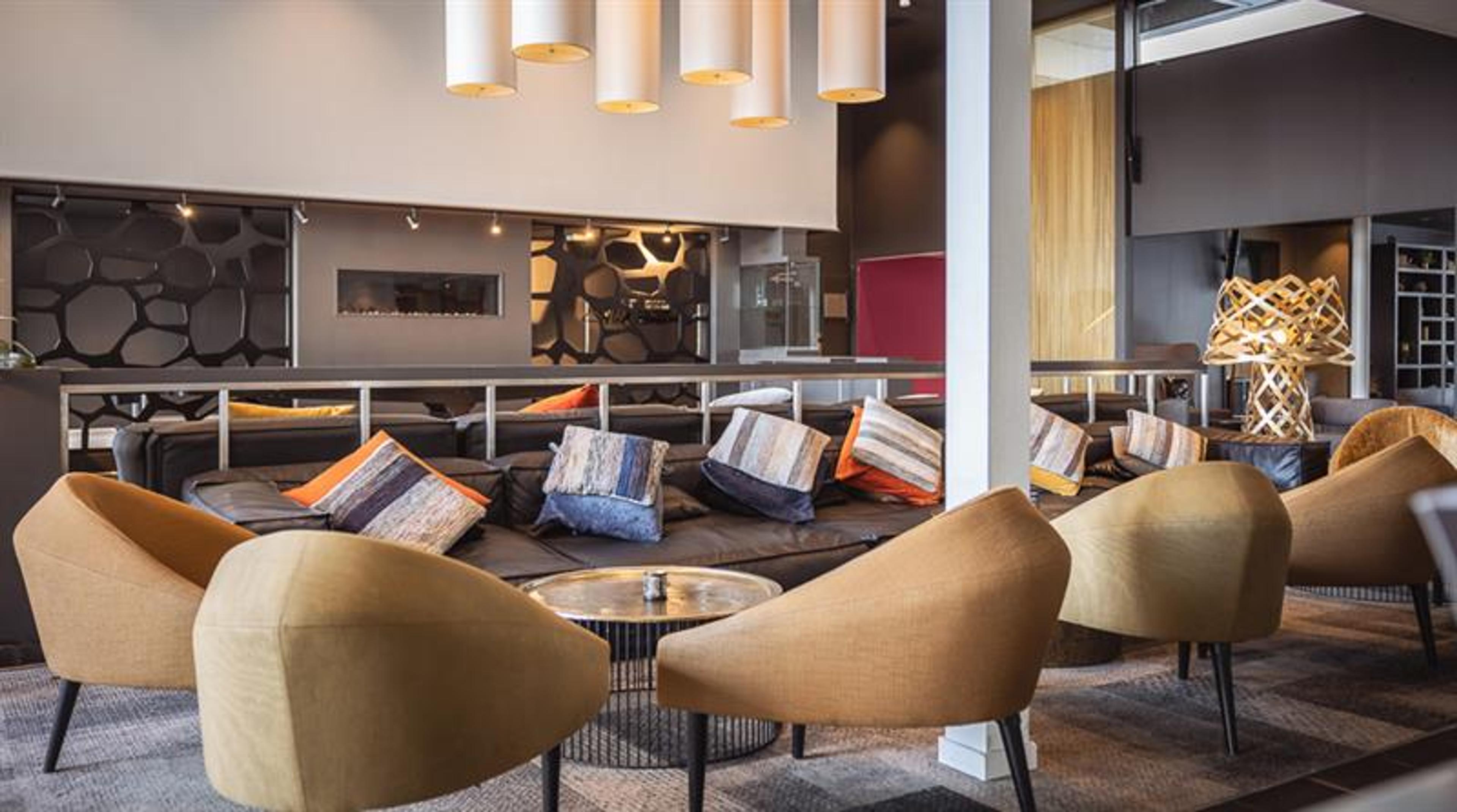 Hotel entrance with modern architecture, parking area, and clear signage.