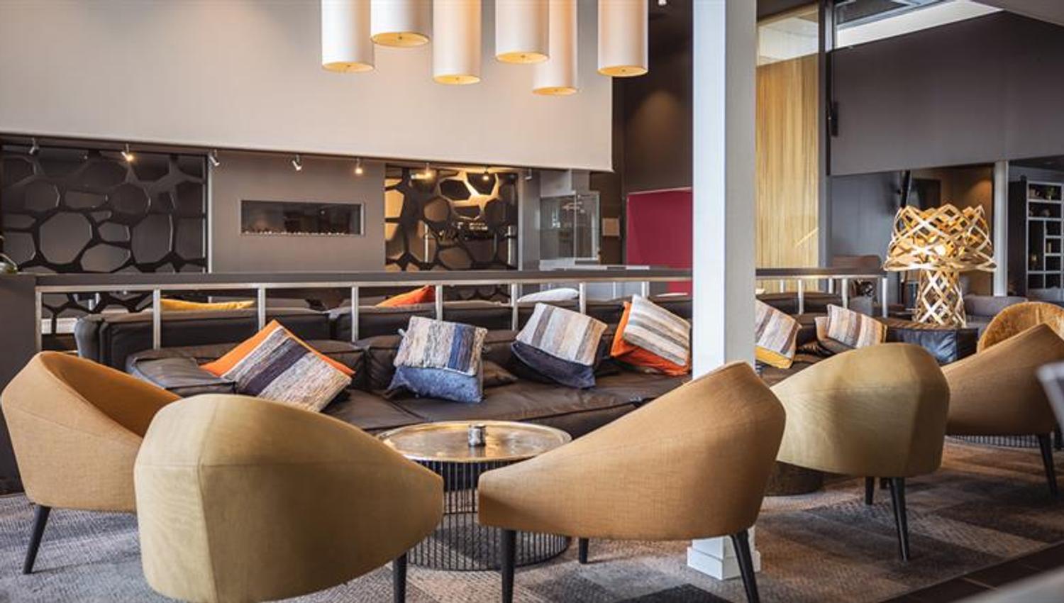 Hotellinngang med moderne arkitektur, parkeringsområde og tydelig skilting