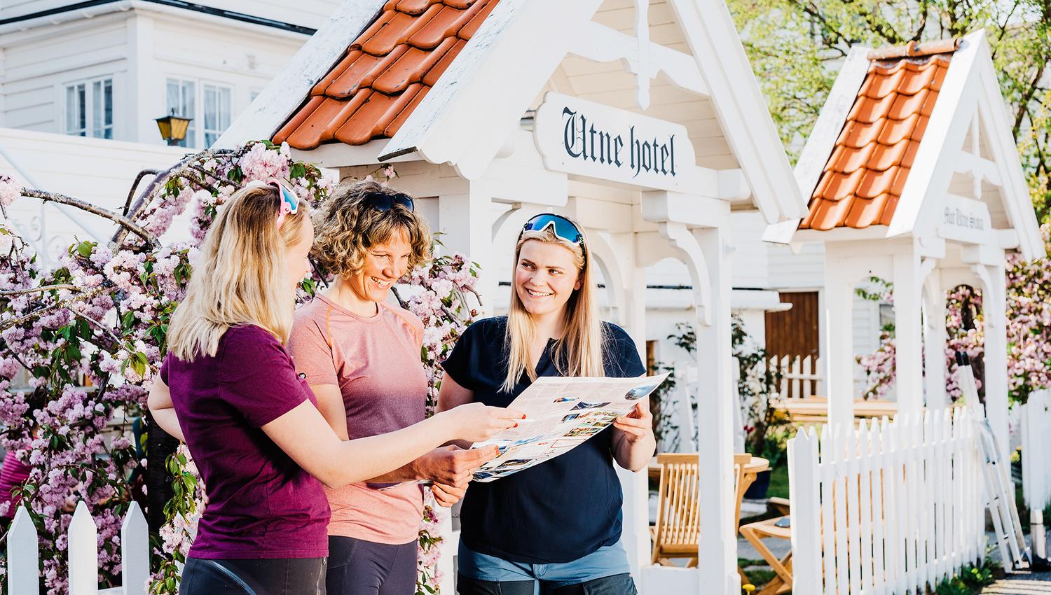 Three hikers planning an adventure in Hardanger outside the charming Utne Hotel.