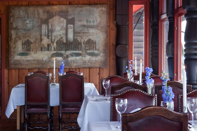 Cozy dining area with set tables with white tablecothes and chairs.
