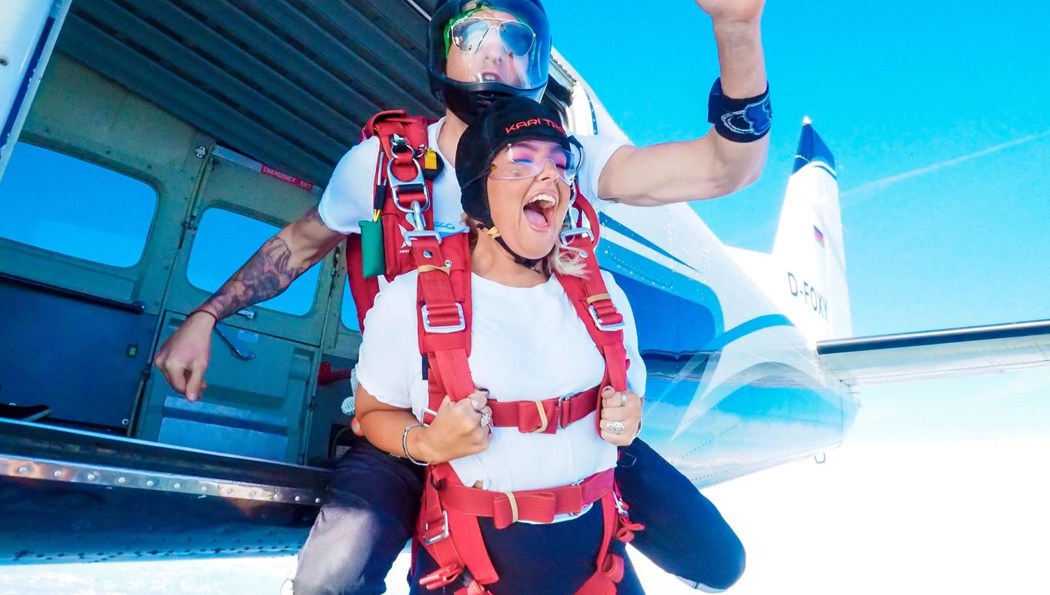 Excited tandem jumpers just after exiting the plane, the plane and sky in the background.
