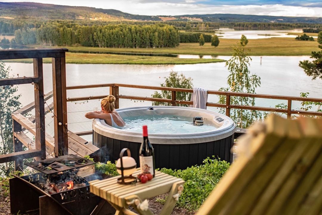 Dame som bader i et bobebad med utsikt over øyeren