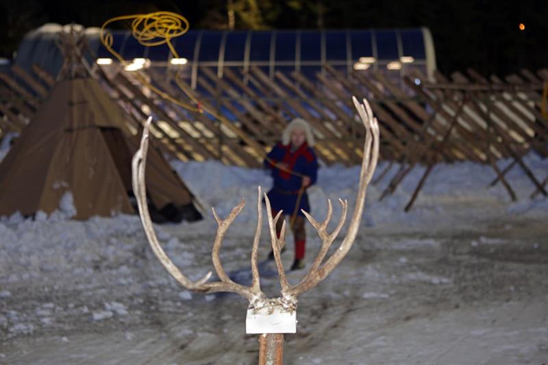 man throwing the lasso towards a reindeer antlers