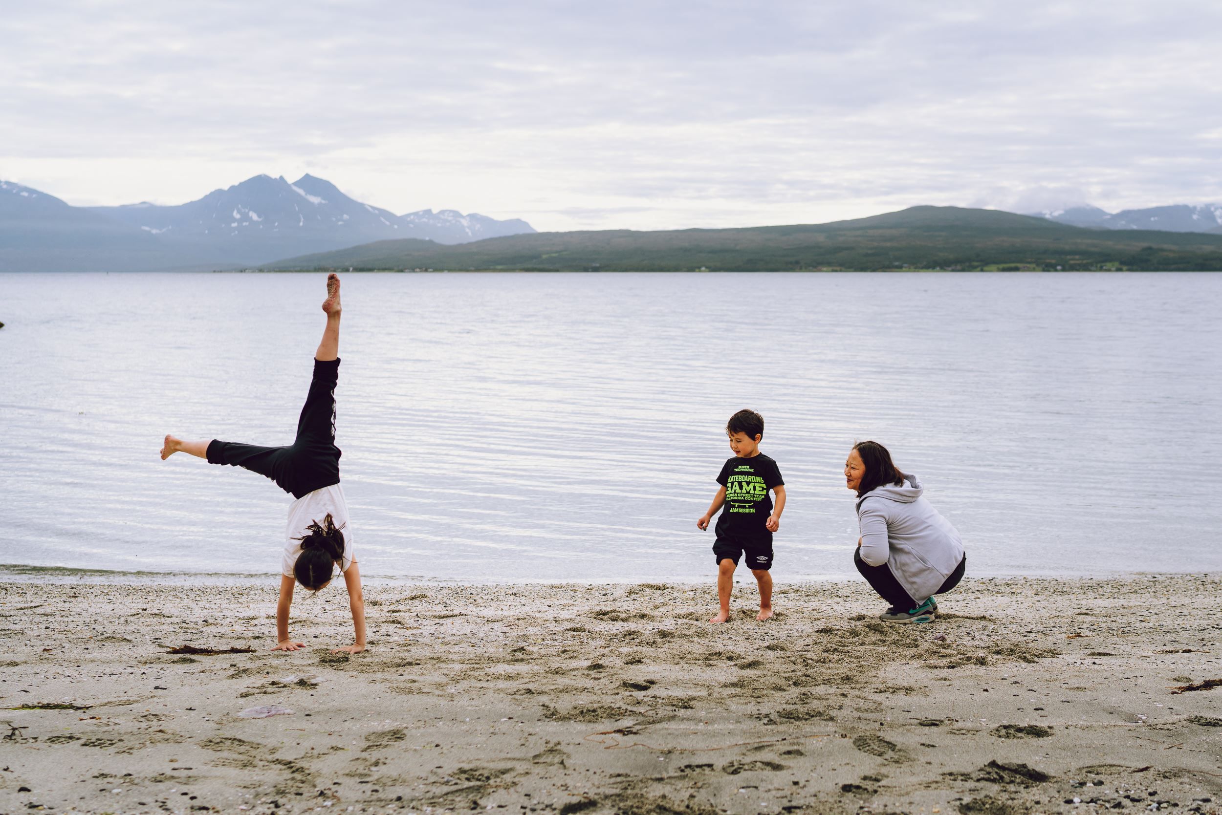 mom and two children playing on the sandy beach