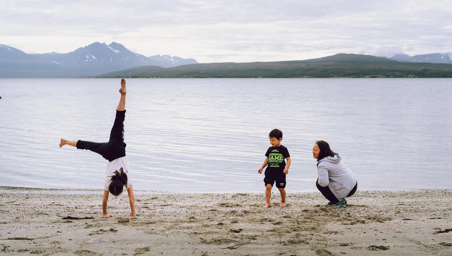 mom and two children playing on the sandy beach