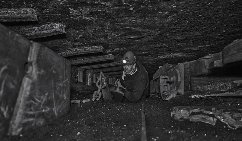 Guest on a guided tour of Mine 3 with a helmet on that has gotten the chance to crawl through the mine tunnels where miners worked in the past