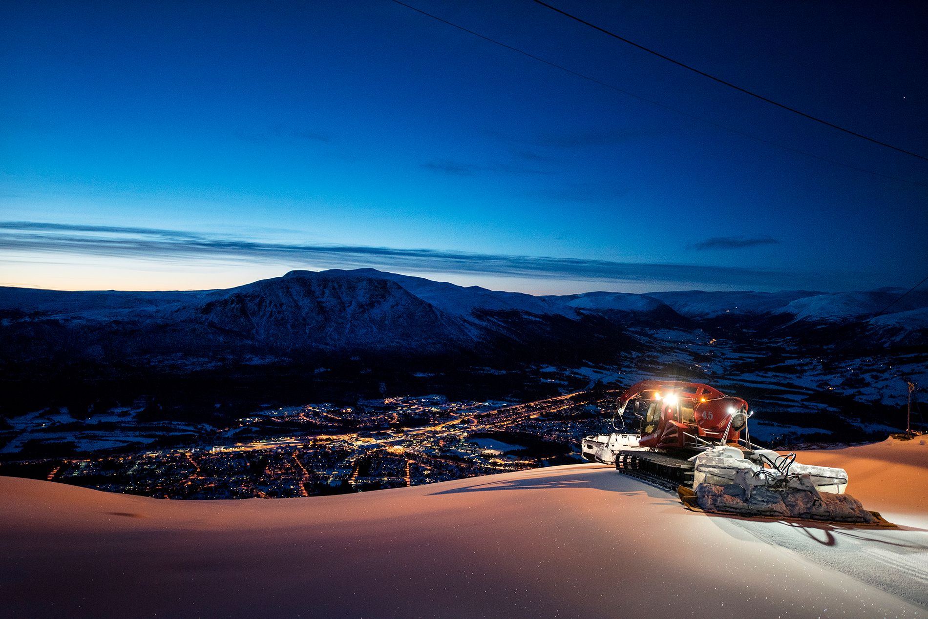 Tråkkemaskina på kveldstid med utsikt mot Oppdal sentrum