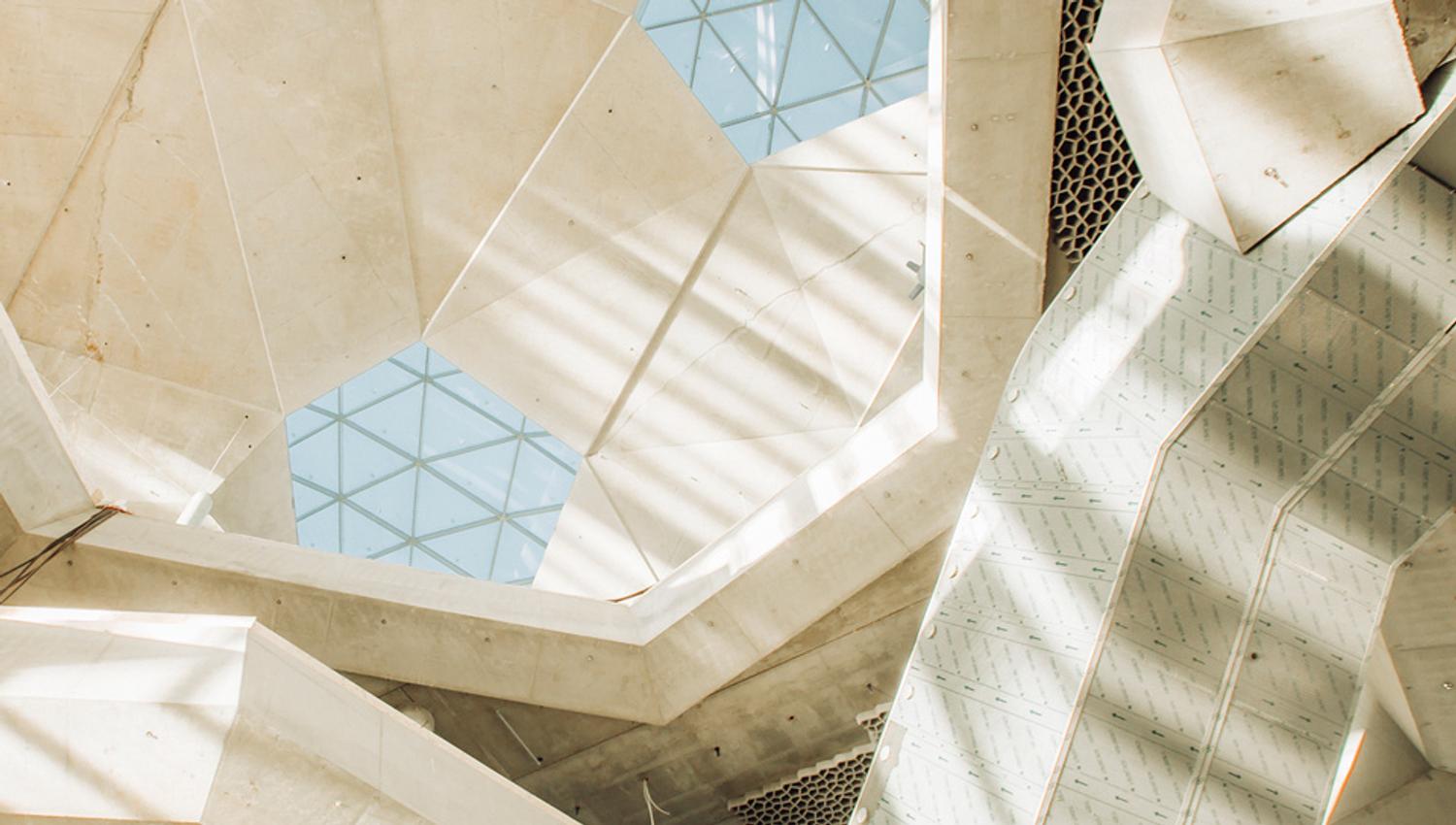 The ceiling inside the library Deichman Bjørvika, taken from below. The sky is visible through pentagonal window scattered across the ceiling full of