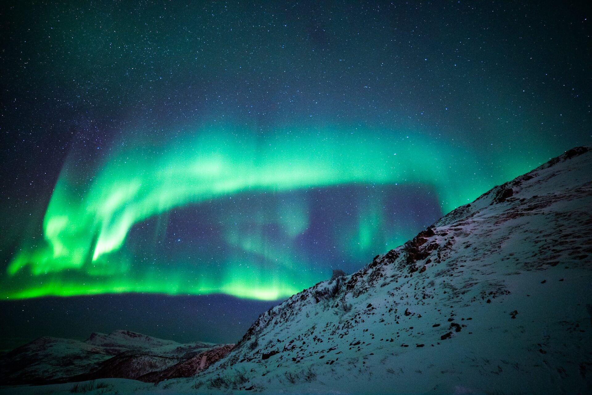 Bilde av nordlyset bak et snødekt fjell