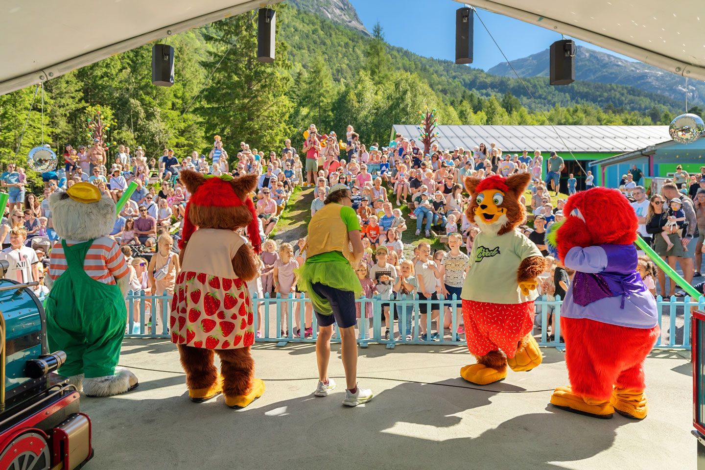 Audience enjoying a live show featuring Mikkelparken's popular mascots on stage