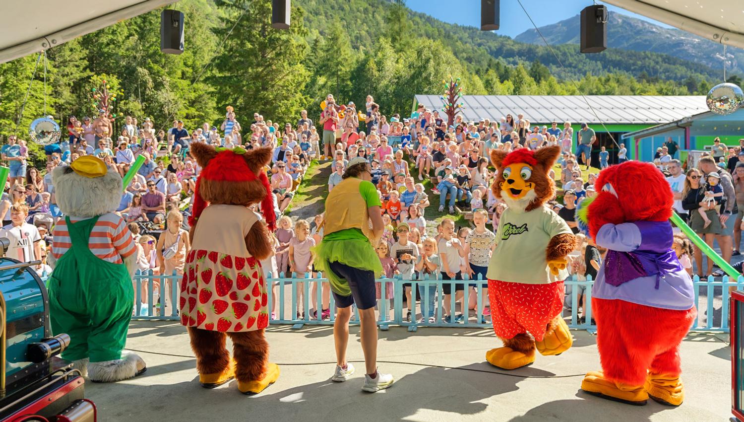 Audience enjoying a live show featuring Mikkelparken's popular mascots on stage
