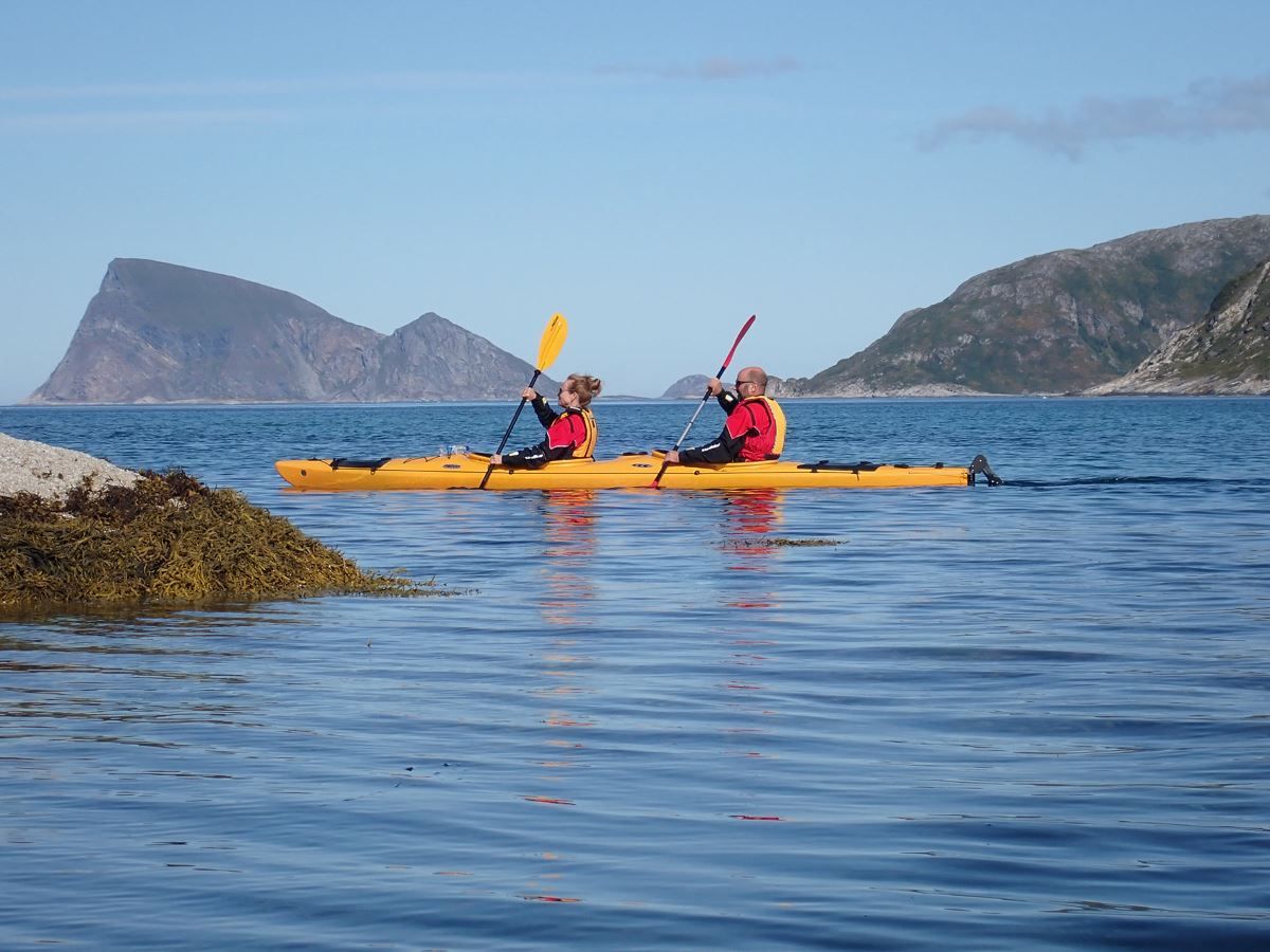 A couple paddle in the sea with the famous Håja mountain in the backgroun