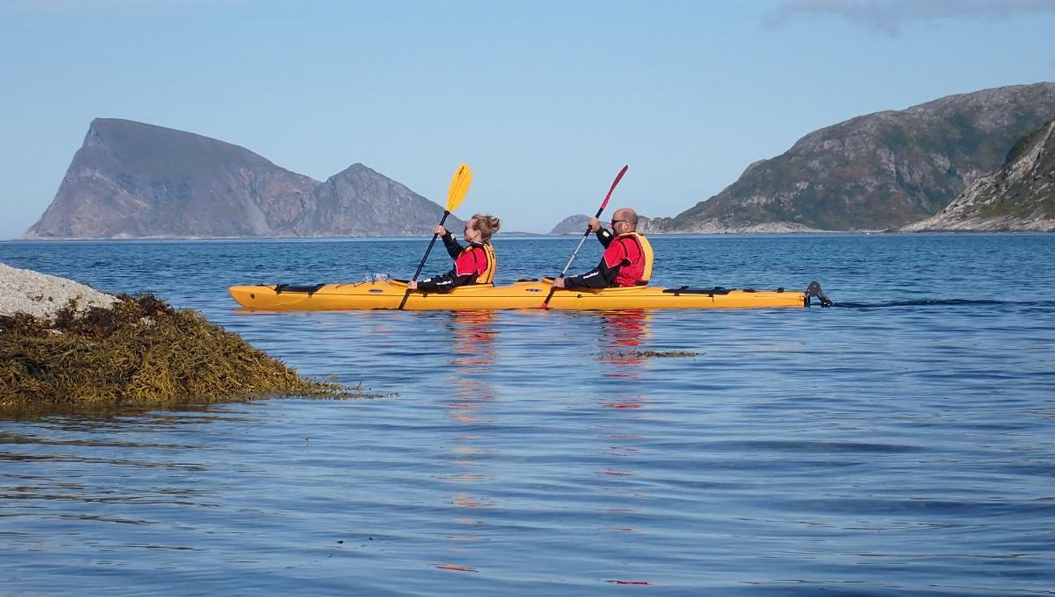 A couple paddle in the sea with the famous Håja mountain in the backgroun
