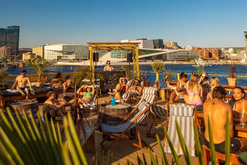 People in swimwear on the fjord terrace in front of the Opera House and the fjord