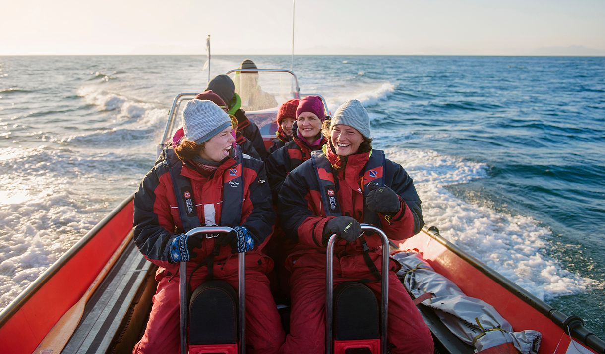 En gruppe med gjester om bord en RIB båt som kjører i fart på en fjord