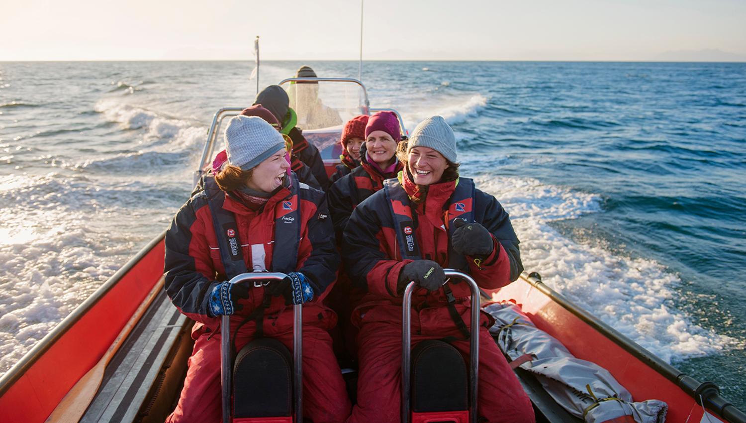En gruppe med gjester om bord en RIB båt som kjører i fart på en fjord