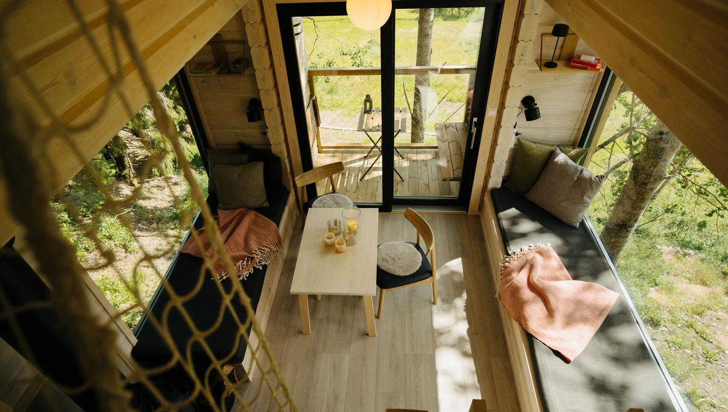Chairs and a table in a room with large windows and scenic views outside.