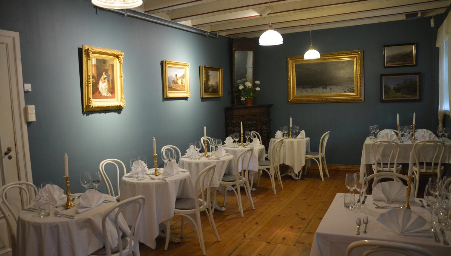 Den elegante spisesalen i Baroniet i Rosendal, dekka til for gjester med stilfull kunst på veggane.