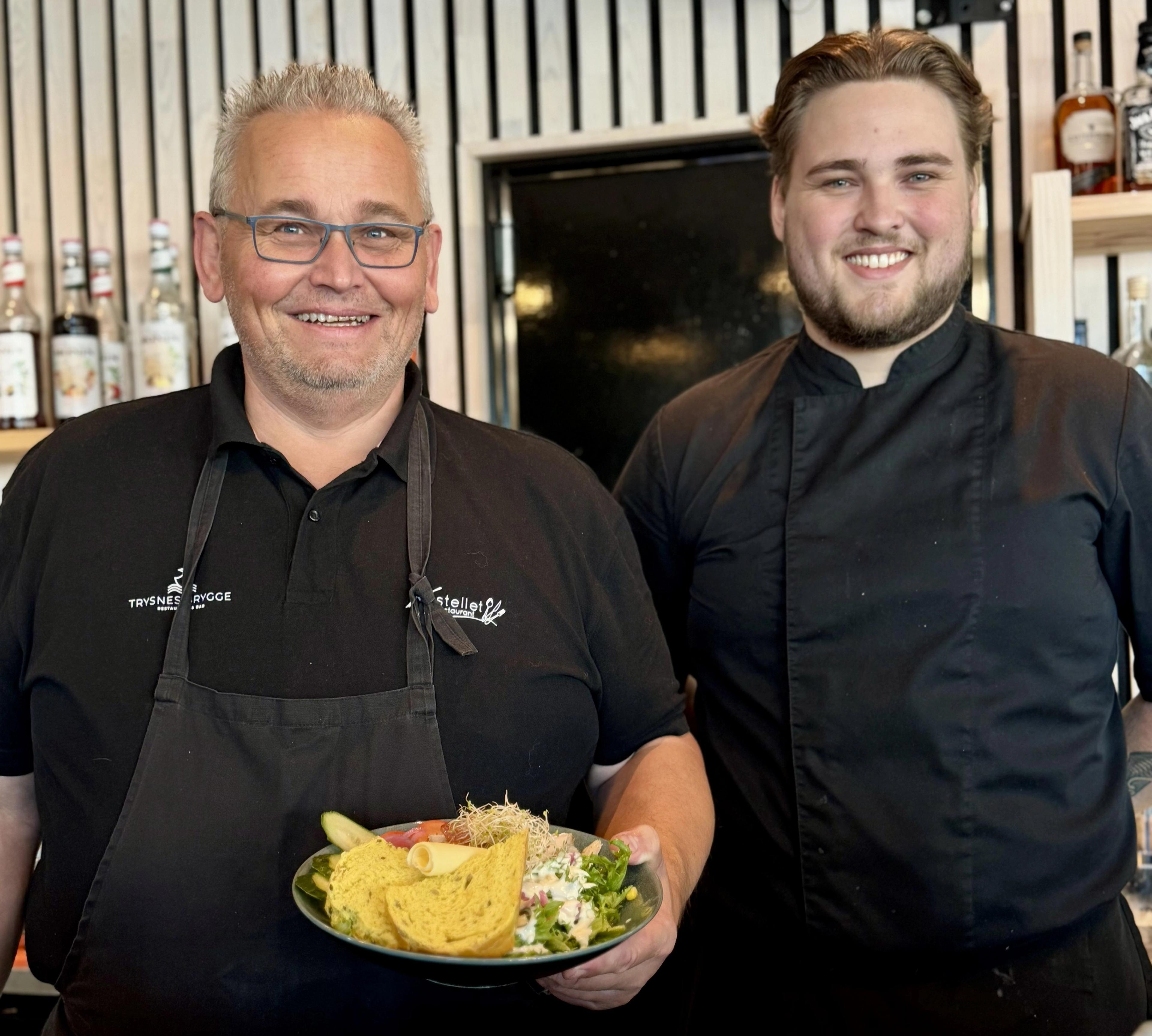 To smilende kokker som viser stolt fram en kyllingsalat