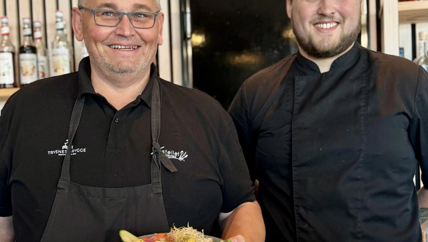 Two smiling chefs proudly showing a chicken salad.