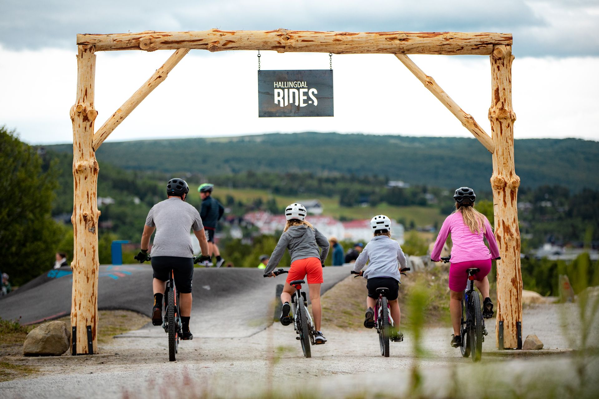 The entrance to the Vestlia Bike Park with two adults and two children on their bikes. 