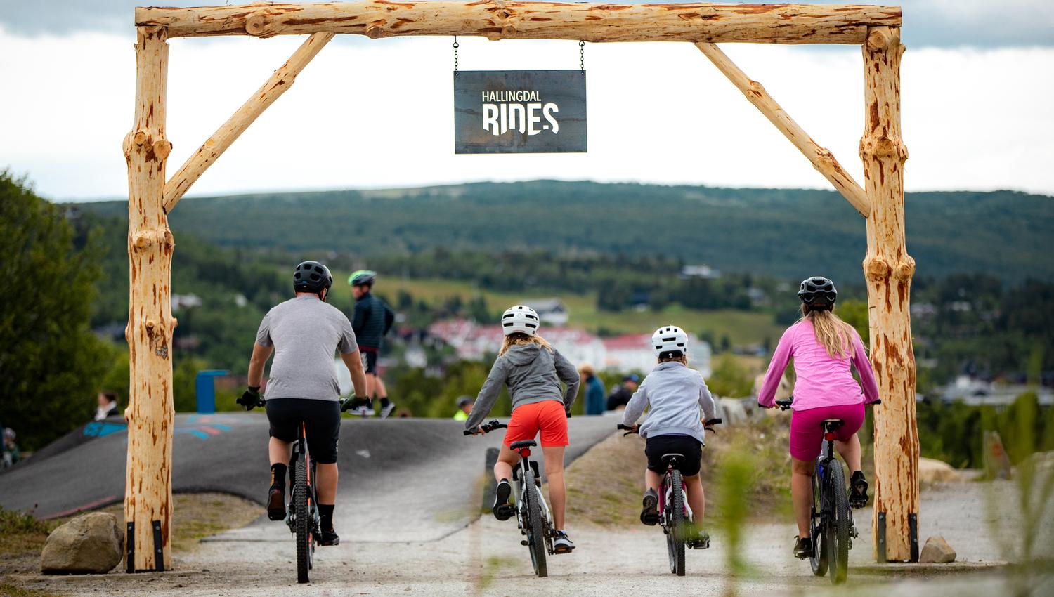 Inngangen til Vestlia Sykkelpark med to voksne og to barn på sykkel.