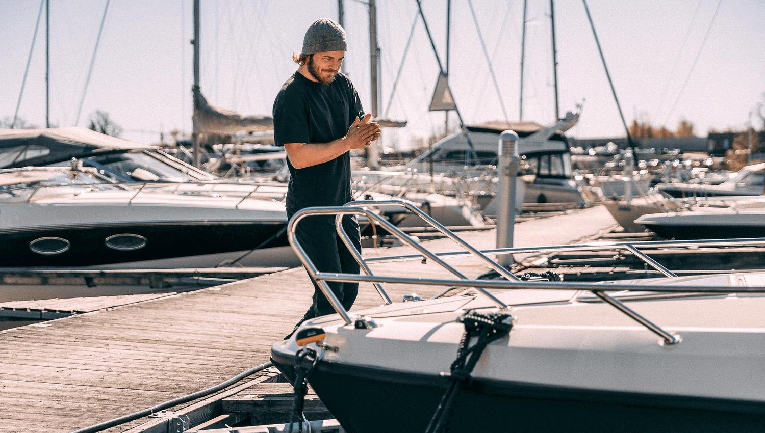 Mann på brygge foran båt