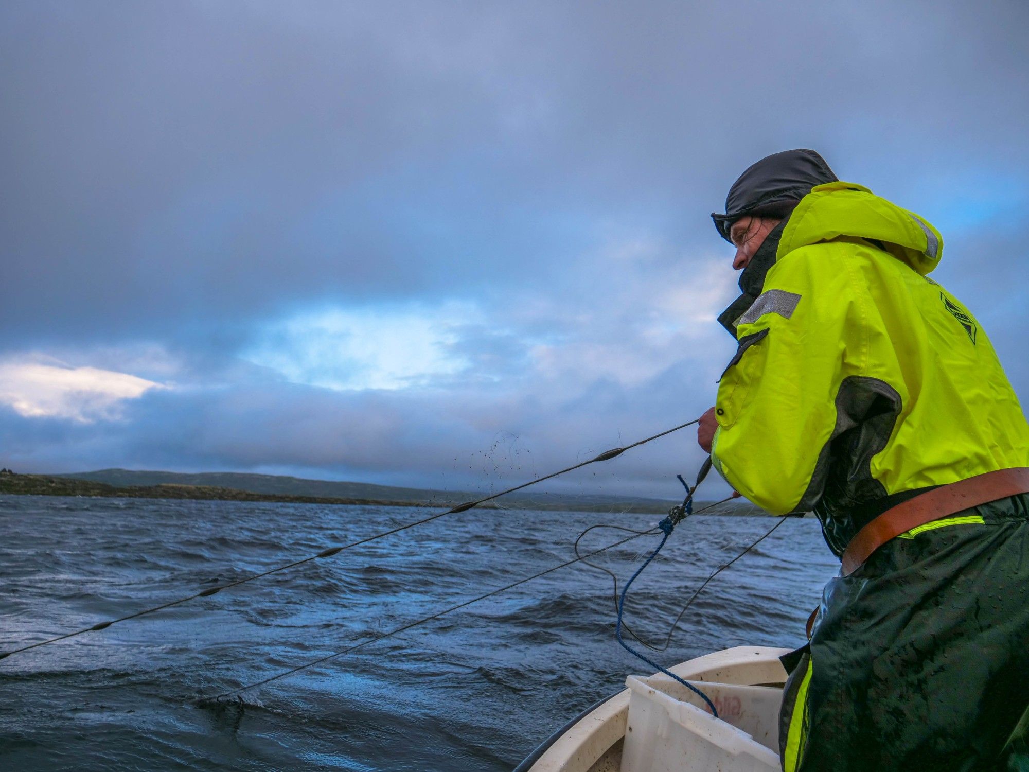 A man hauls in fishing nets from a boat on Hardangervidda.