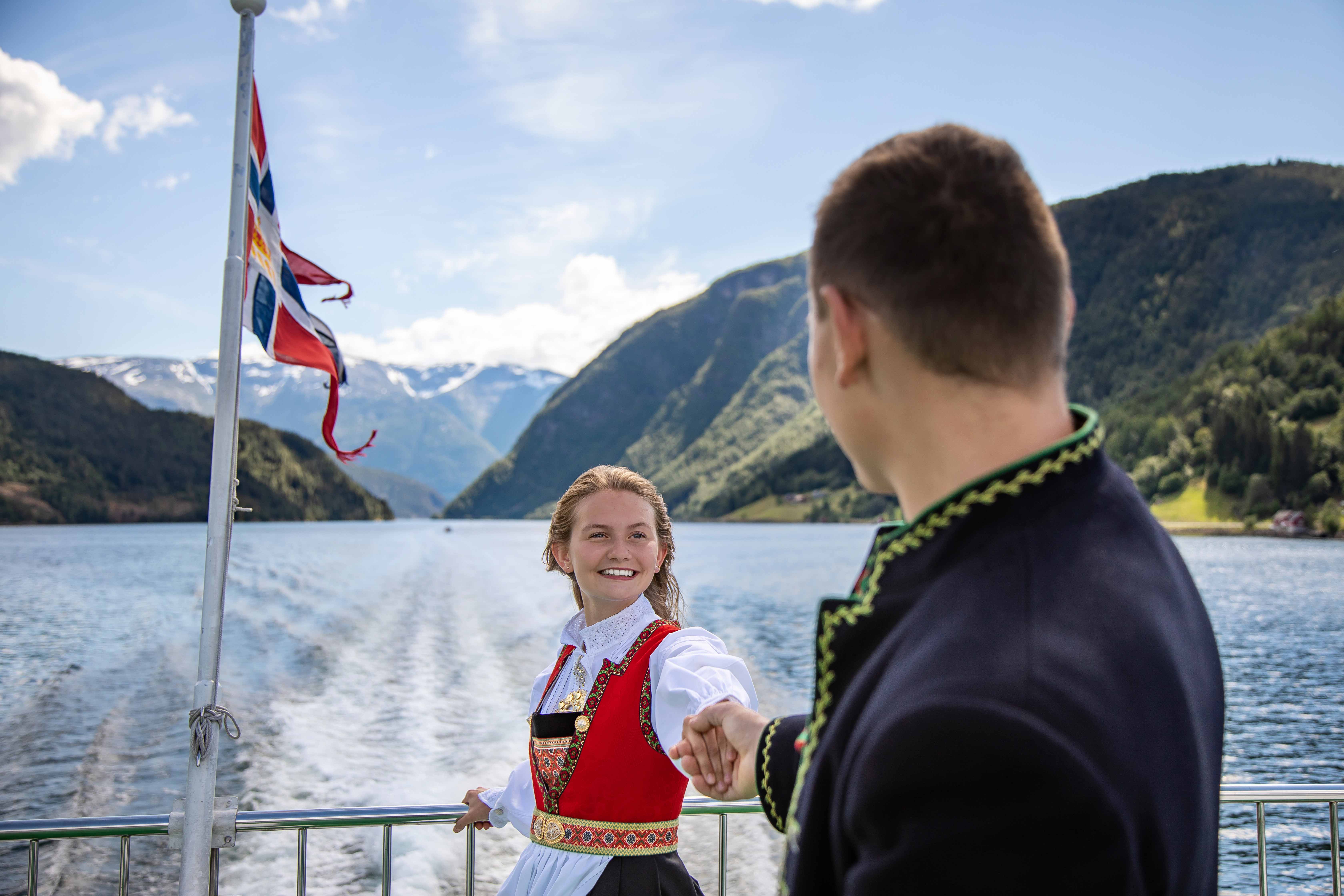 Mann og dame i bunad på Hardangerfjorden.