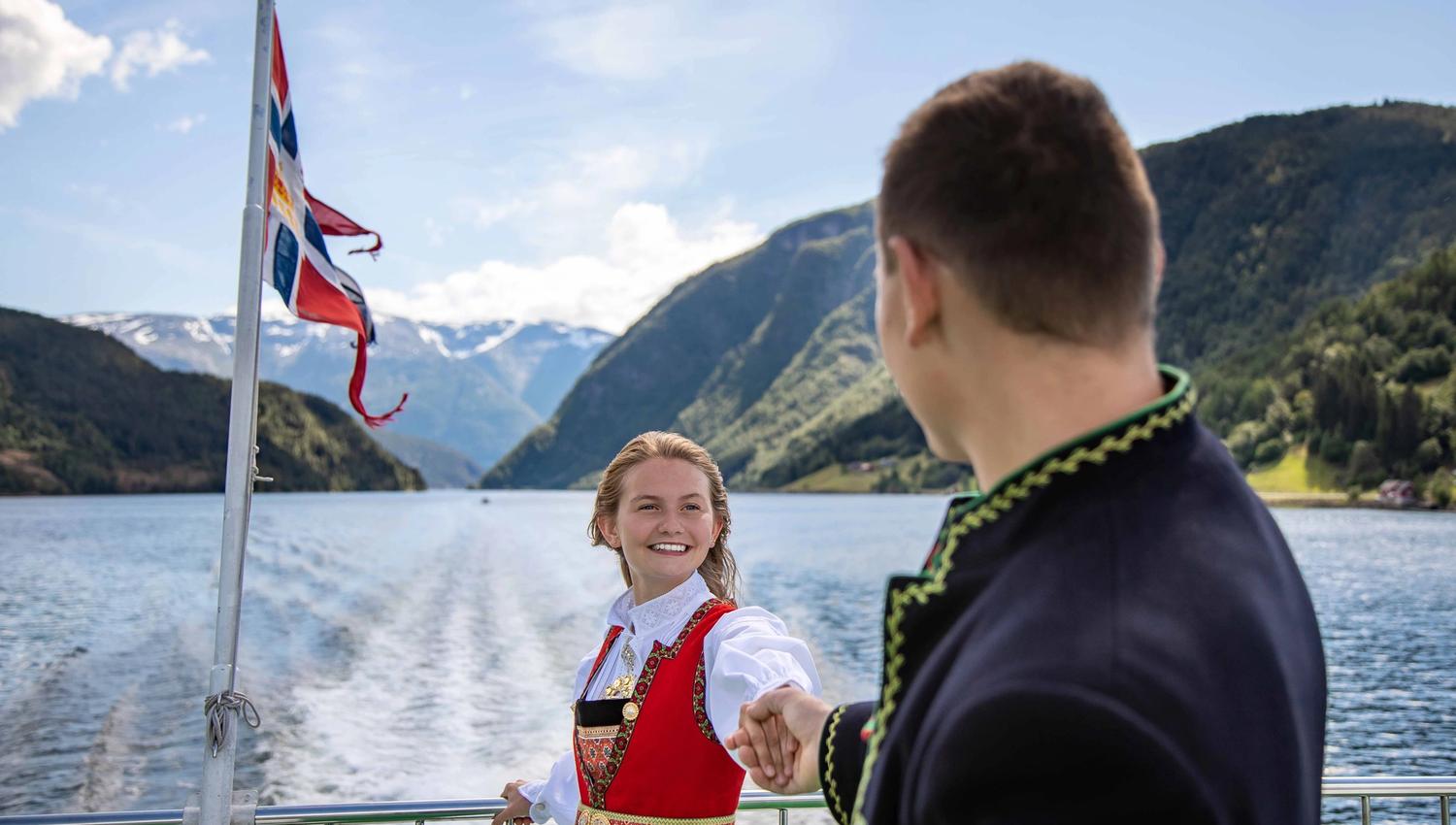 Mann og dame i bunad på Hardangerfjorden.