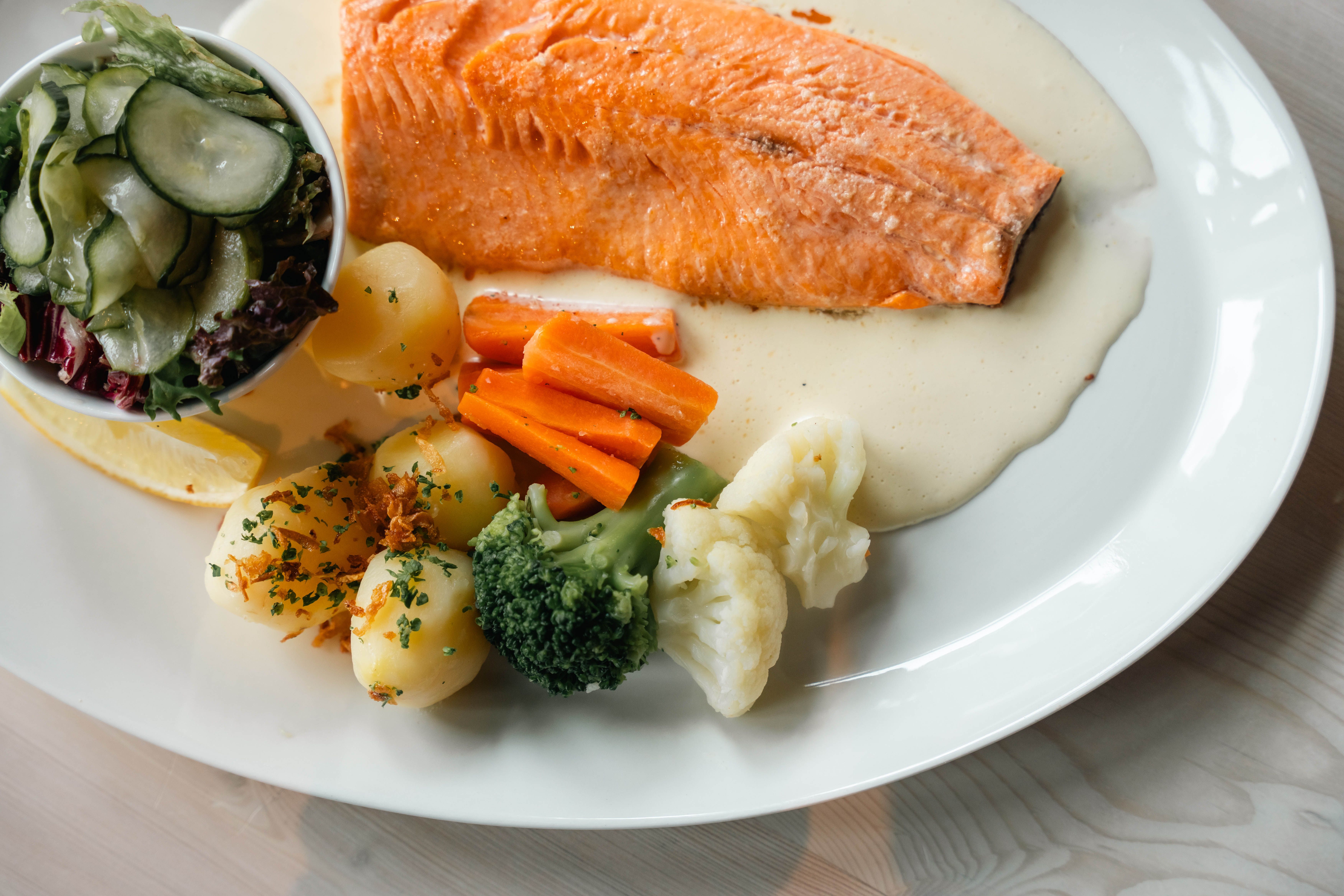 En tallerken med fjellørret, poteter, salat og fløtesaus.