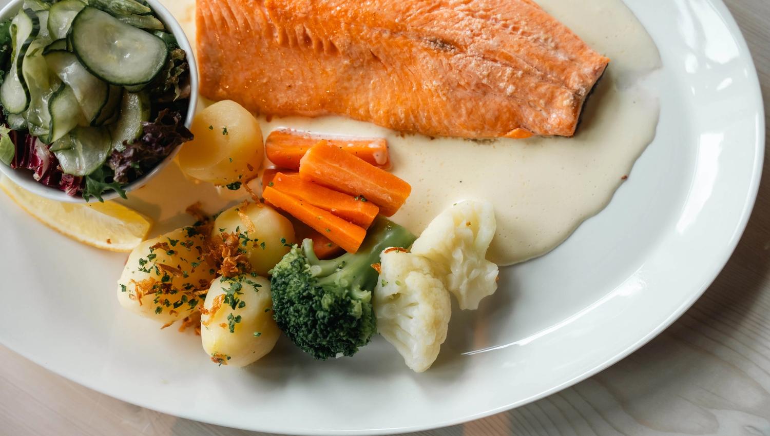 En tallerken med fjellørret, poteter, salat og fløtesaus.