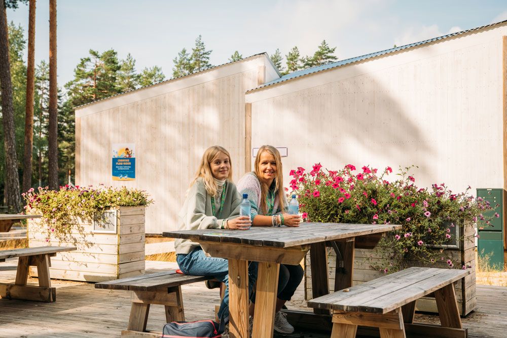 2 jenter sitter på en piknikbenk i en av de rolige områdene i Bø Sommarland
