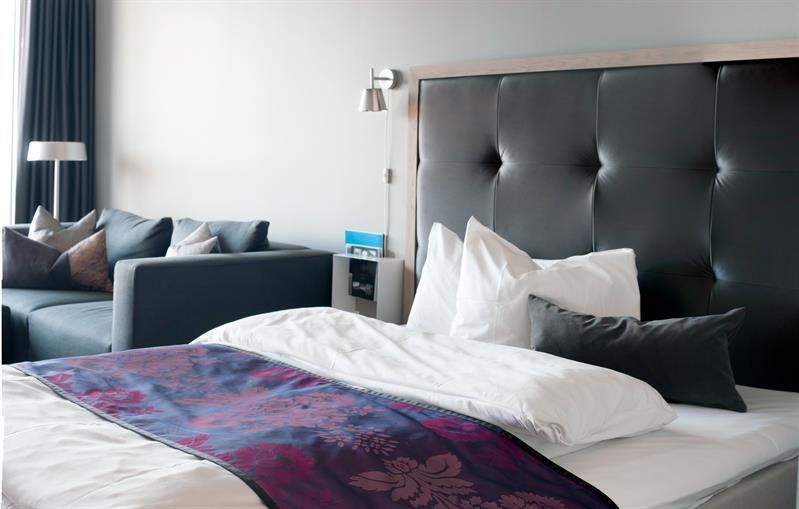 Junior suite, seng og sofa, mørk innredning. Foto
