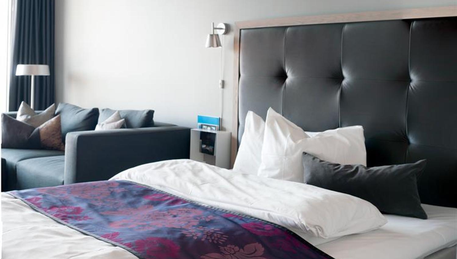 Junior suite, seng og sofa, mørk innredning. Foto