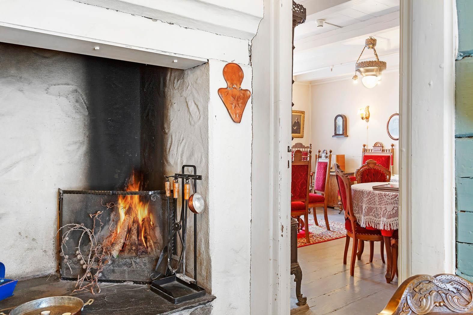 Open peis og nostalgisk spisestove med raude stolar på Jaunsen Gjestgjevarstad i Hardanger.