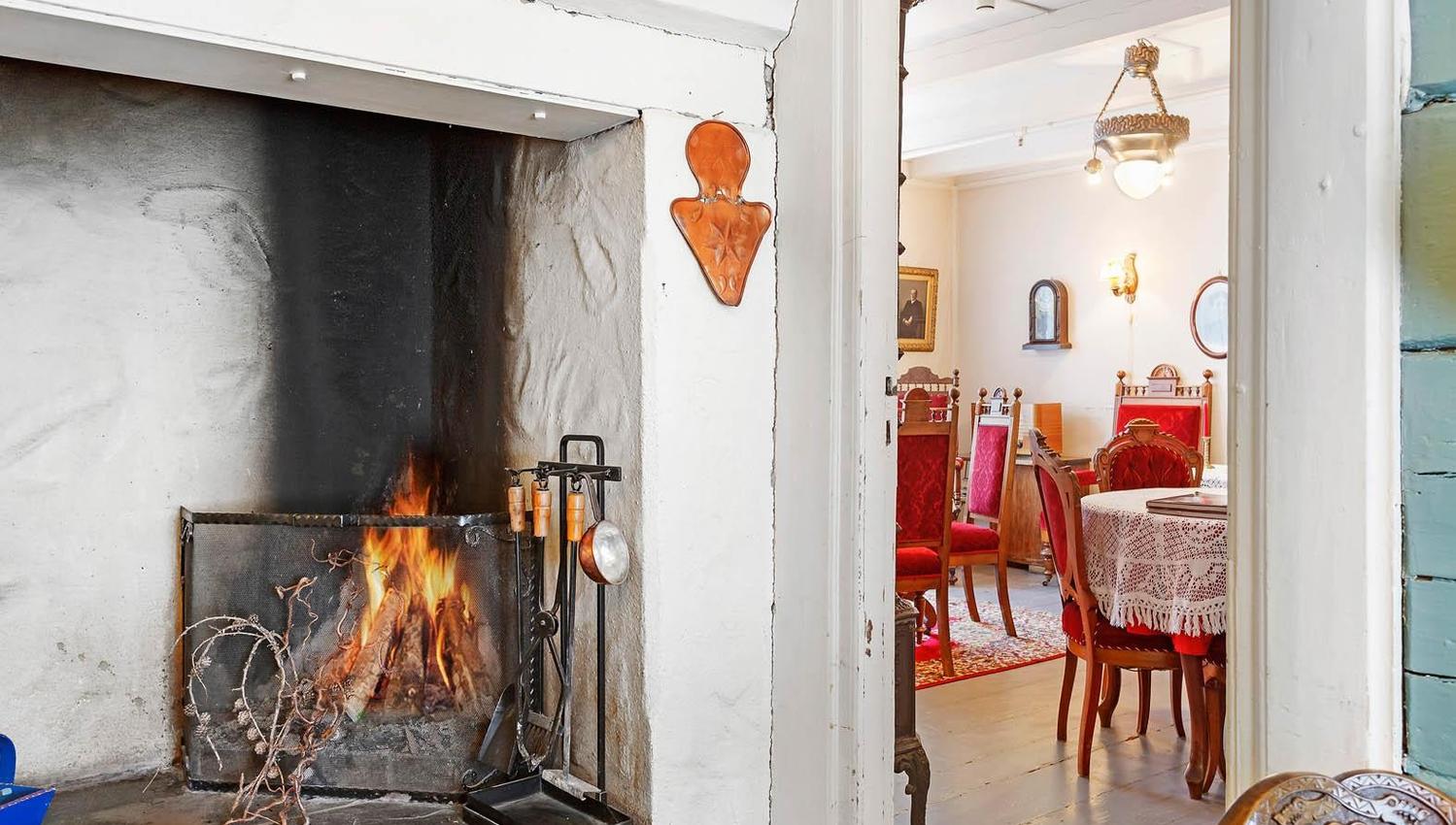 Open fireplace and nostalgic dining room with red chairs at Jaunsen Guesthouse in Hardanger.