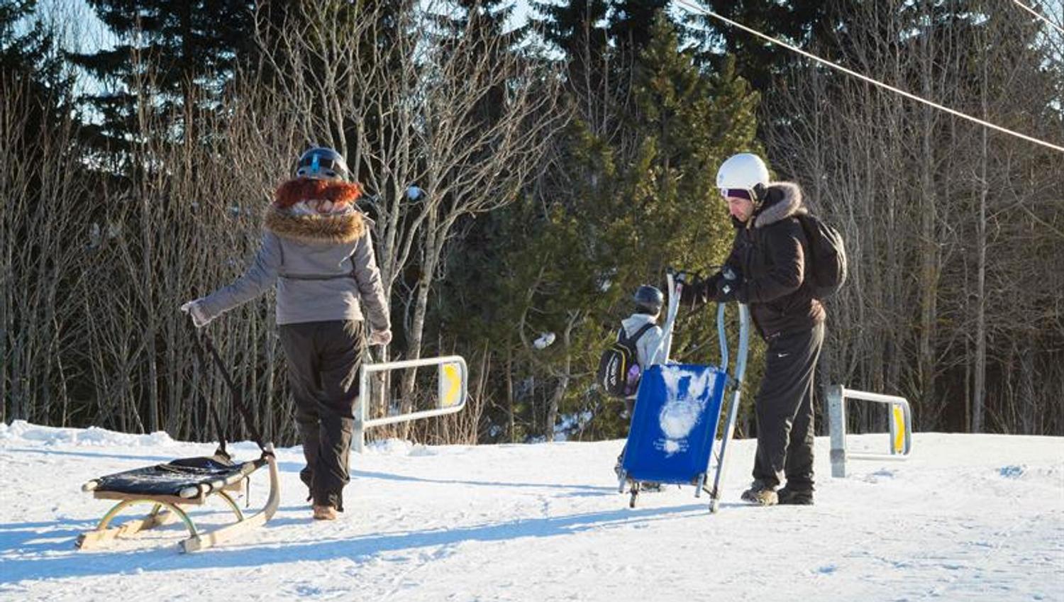 To personer som trekker hver sitt akebrett nederst i bakken.
