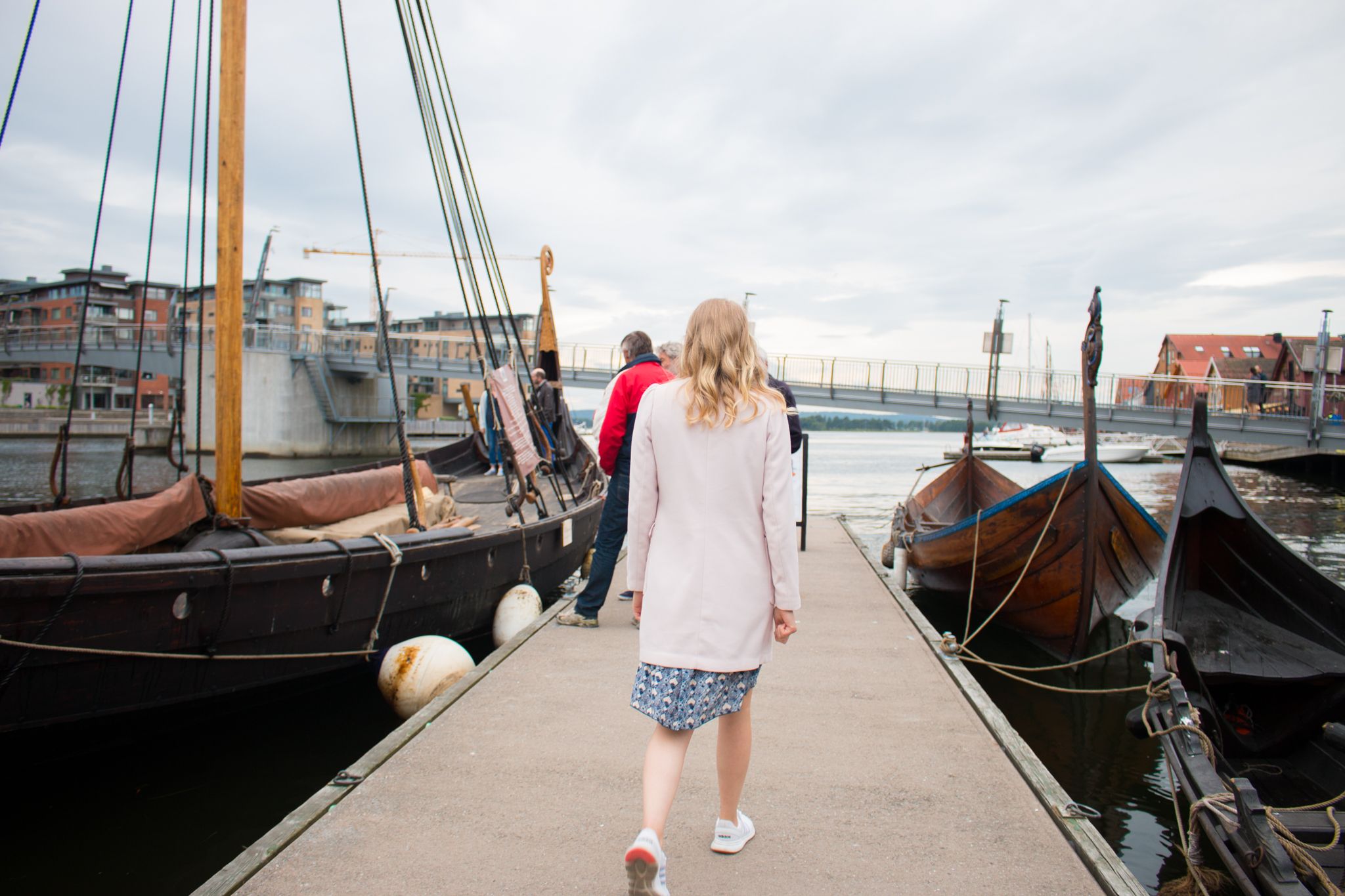 A lady walks on the pier in Tønsberg towards the Viking ship Saga Oseberg