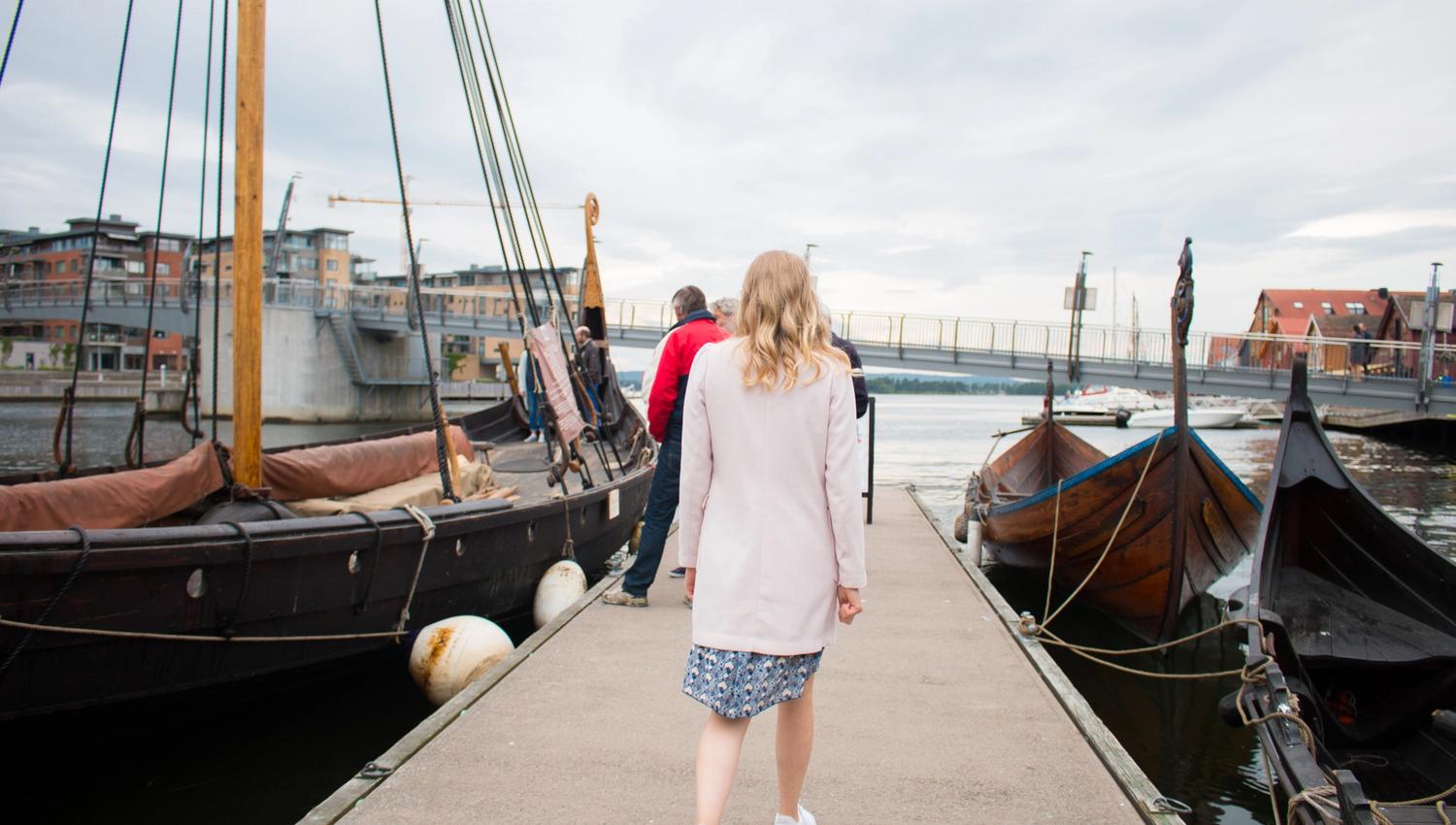 A lady walks on the pier in Tønsberg towards the Viking ship Saga Oseberg