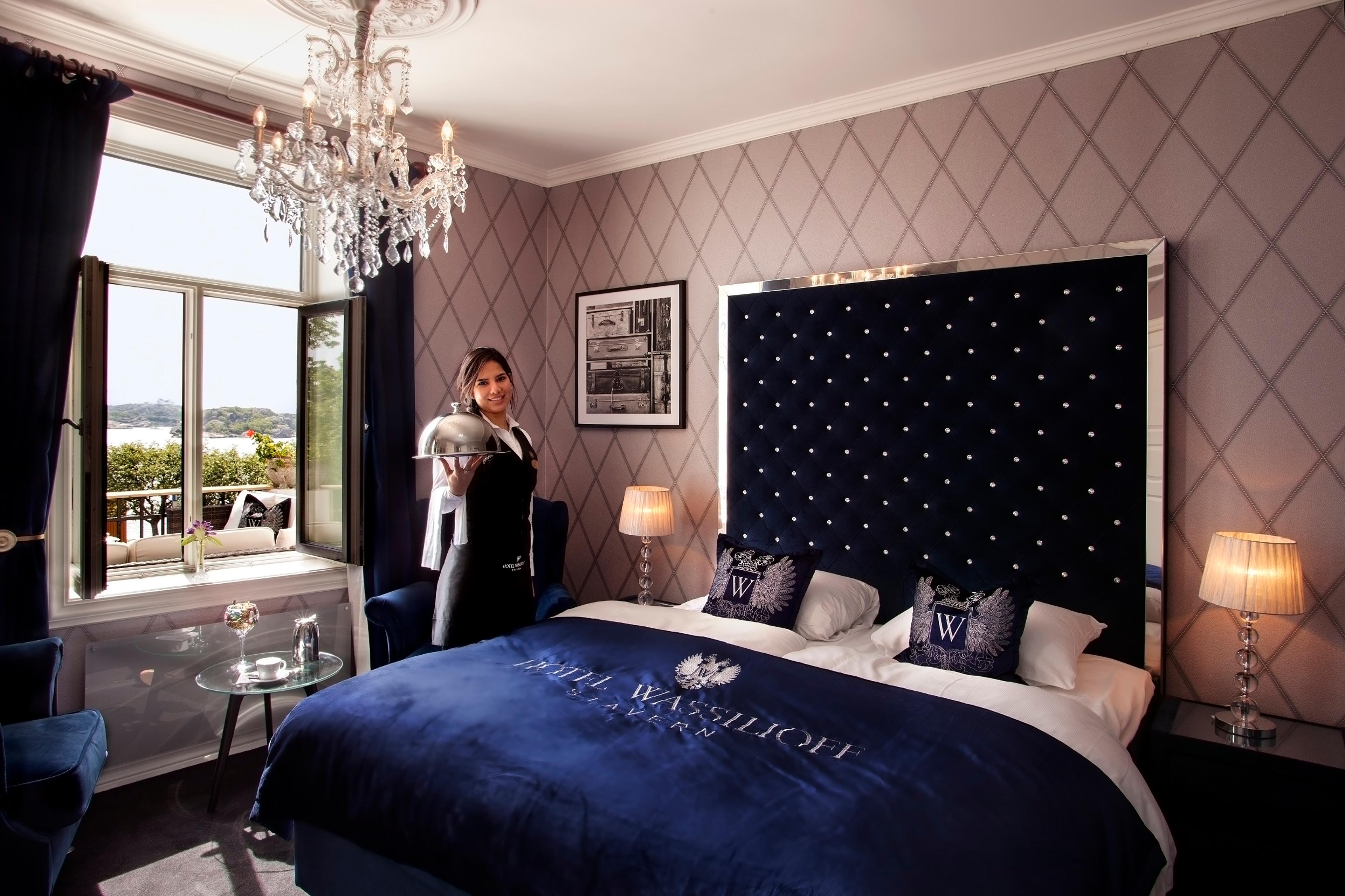 A maid holds out a serving dish inside a hotel room.
