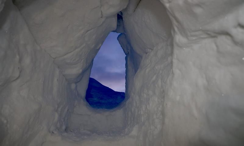 Inngangen til isgrotten med den blå kveldshimmelen i bakgrunnen