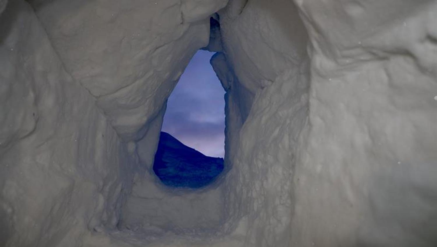 Inngangen til isgrotten med den blå kveldshimmelen i bakgrunnen