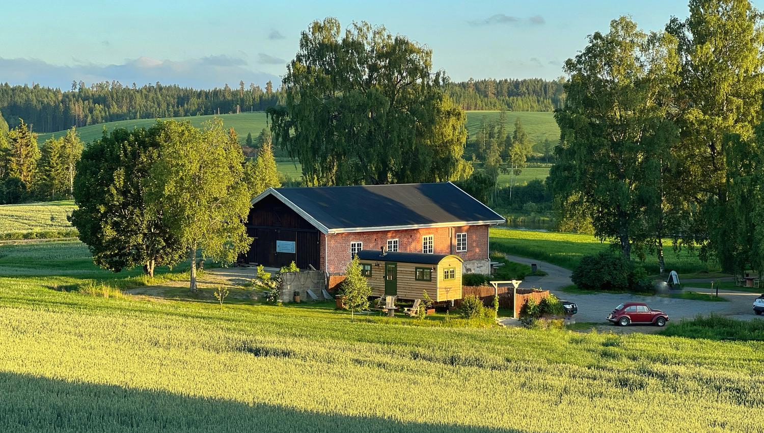 Shepherd´s Hut oversiktsbilde med en låve, åker og en gammel bil