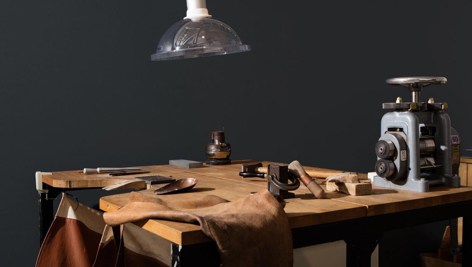 Arbeidsbenk med verktøy og lærarbeid under lampe
