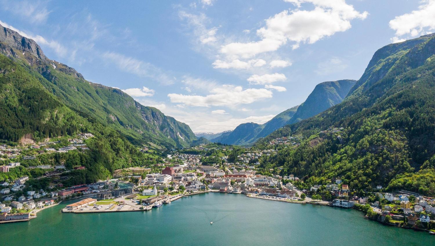 Luftfoto av Odda ved fjorden med hus og båter langs vannkanten.