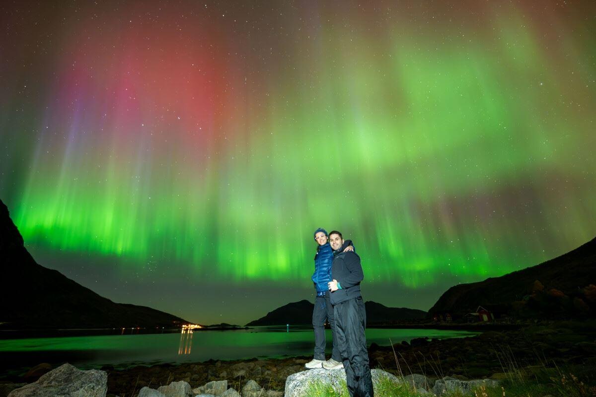 Two guests pose in front of an extravagant Northern Lights show